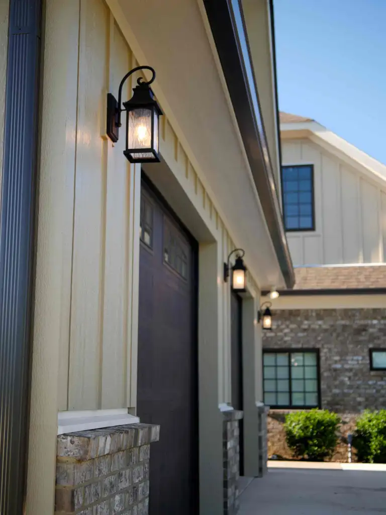 Board-and-batten wall with a lantern sconce above a brick base, the house in the background, near Franklin, Tennessee
